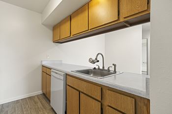 A kitchen with a white counter top and wooden cabinets.